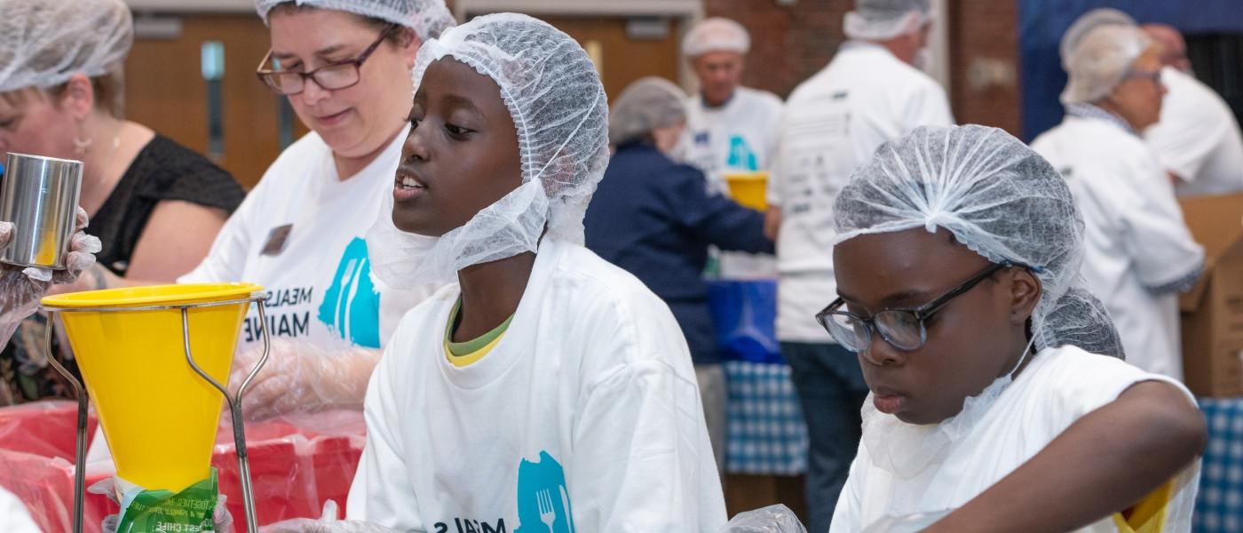 Two children volunteers help pack food for Meals for Maine